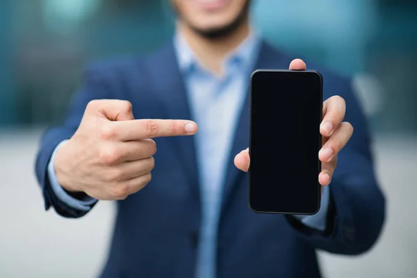 Невпізнаваний бізнесмен вказує на смартфон з порожнім екраном — стокове фото