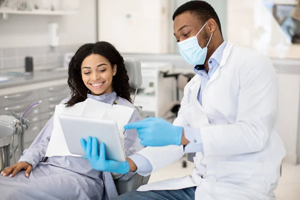 Μαύρος Οδοντίατρος Γιατρός με Ψηφιακή Tablet Συμβουλευτική Γυναίκα Ασθενής Σε Σύγχρονη Κλινική — Φωτογραφία Αρχείου