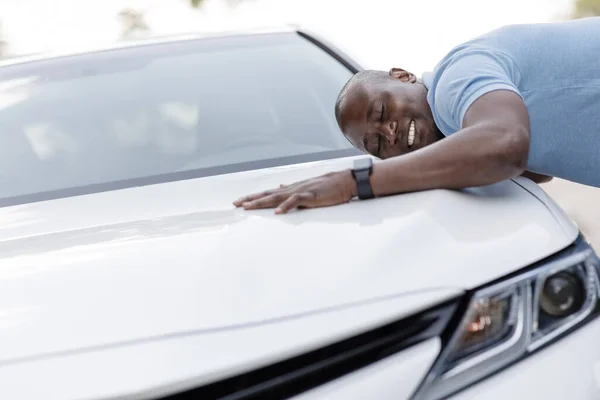 Εκστατικός μαύρος άντρας ακουμπά στο πολυτελές αυτοκίνητο του ονείρου του. — Φωτογραφία Αρχείου