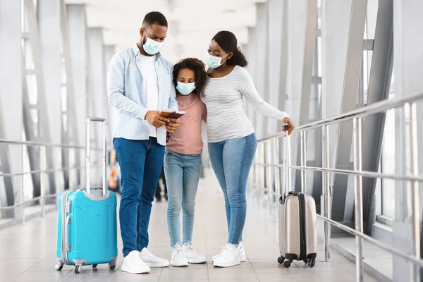 Familia negra enmascarada viajando, mirando documentos en el aeropuerto —  Fotos de Stock