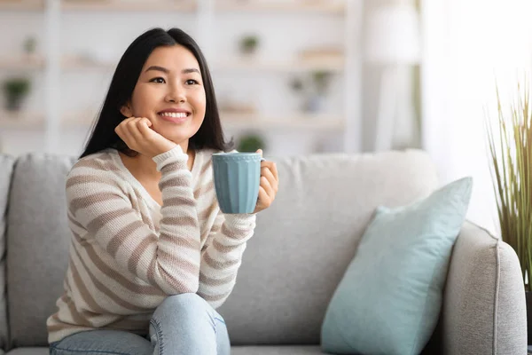 Weekend thuis. gelukkig koreaans dame ontspannen op bank met koffie — Stockfoto