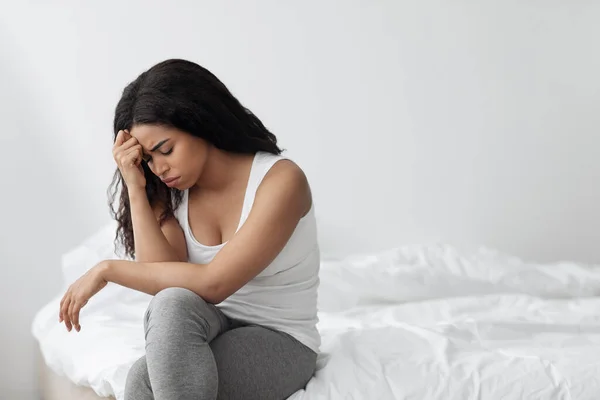 Depression concept. Unhappy black lady sitting on bed alone and feeeling upset after breakup with boylfriend or husband — Stock Photo, Image