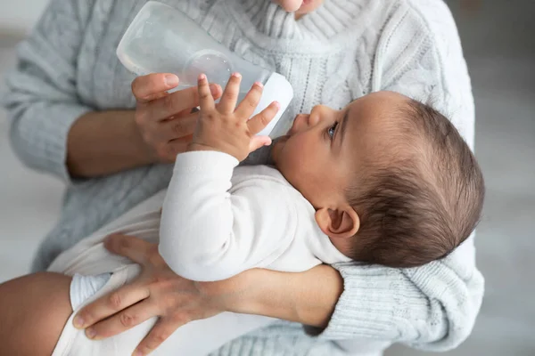 Cute little black baby drinking water from bottle — Stock Photo, Image