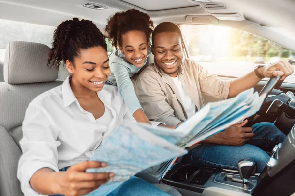 Веселая африканская семья смотрит на карту дорог, сидя в автомобиле — стоковое фото