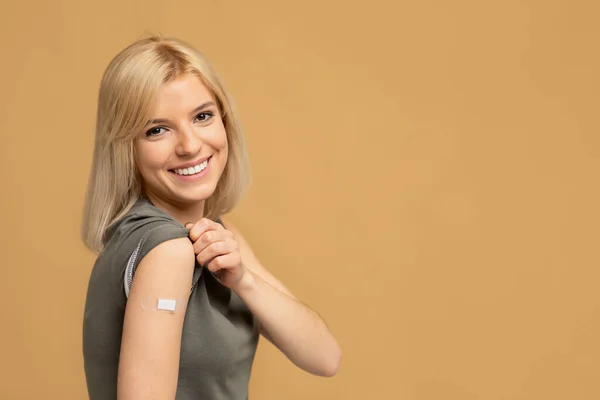 Antivirale Impfung. Geimpfte Frau zeigt Arm mit Klebeverband nach Covid-19-Impfung, freier Raum — Stockfoto