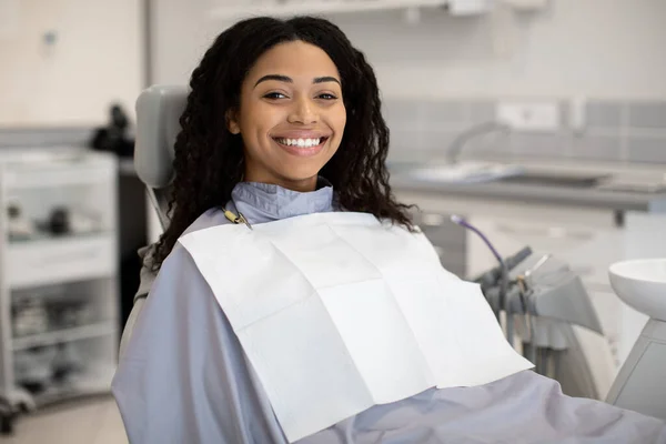 Стоматологічне лікування. Усміхнена афроамериканська жінка сидить у стоматологічній клініці — стокове фото