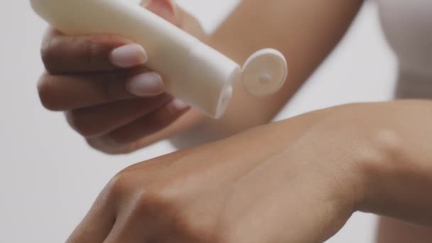 Kosmetika pro péči o tělo. Nerozpoznatelná afroamerická žena mačkající hydratační krém na ruce, zpomalený pohyb — Stock video