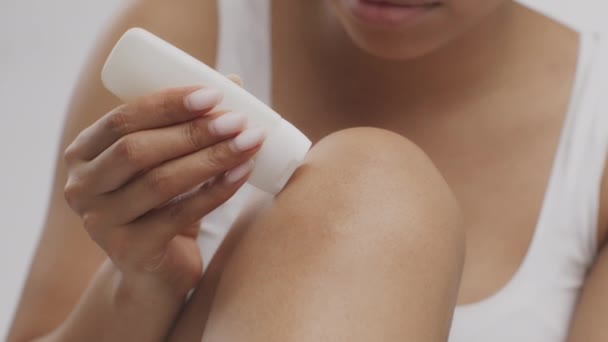 Primer plano de irreconocible mujer afroamericana aplicando crema nutritiva natural en la pierna lisa, cámara lenta — Vídeo de stock