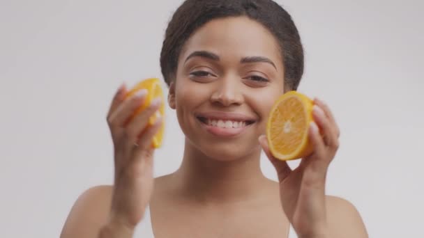 皮肤用维生素C 。年轻而漂亮的非洲裔美国女士，两腿穿橙色衣服，笑着与它合影 — 图库视频影像