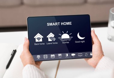 Kullanılan simgeli uygulamalı dijital tablet kullanarak akıllı evi kontrol eden kadın
