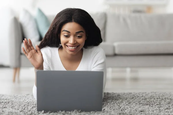 Chat online. Sorridente signora afroamericana con computer portatile fare videochiamate, agitando mano alla webcam, a riposo a casa — Foto Stock