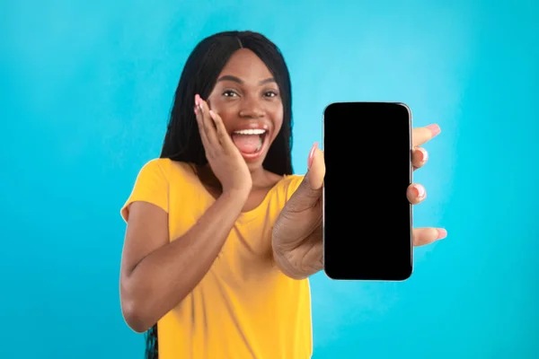 Emocionada dama afroamericana mostrando la pantalla del teléfono en fondo azul — Foto de Stock