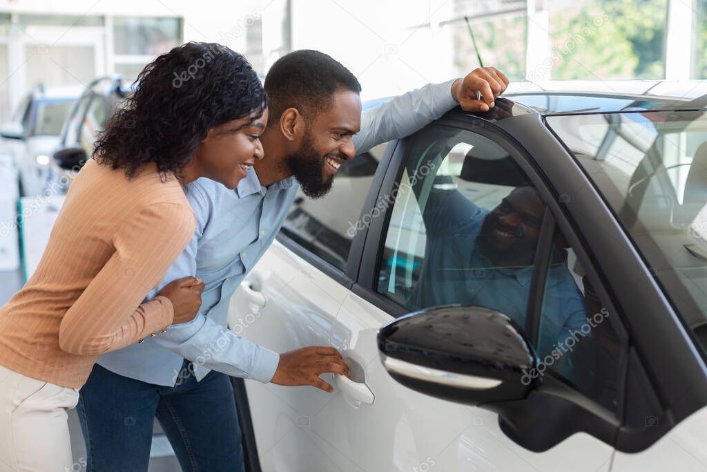 New Car. Excited Black Spouses Looking At New Automobile In Dealership Office