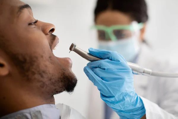 Dentista preto Doctor Lady usando broca dentária para tratamento de dentes de pacientes do sexo masculino — Fotografia de Stock