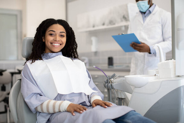 Happy Young African Woman Sitting In Chair During Appointment In Stomatologic Clinic