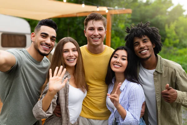 Multi-etnische jonge vrienden nemen selfie samen in de buurt van camper, het maken van verschillende gebaren en glimlachen naar de camera — Stockfoto