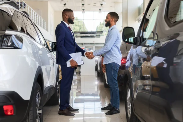 Vendedor de carro preto apertando as mãos com o cliente no moderno centro de negócios — Fotografia de Stock