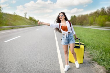 Neşeli milenyum hanımefendisi arabasına biniyor, otobanda bavuluyla arabaya biniyor, kırsalda otostop çekiyor, fotokopi çekiyor.