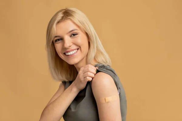 Ich habe meinen Covid-19-Impfstoff bekommen. Aufgeregte junge Frau zeigt geimpften Arm nach antiviraler Injektion, beiger Hintergrund — Stockfoto