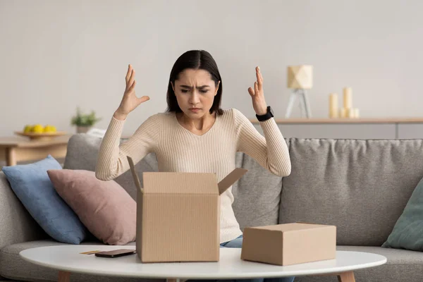 Boos, ongelukkig, verward duizendjarige arabische vrouw uitpakken pakket, verkeerd of gebroken, online winkel bestelling — Stockfoto