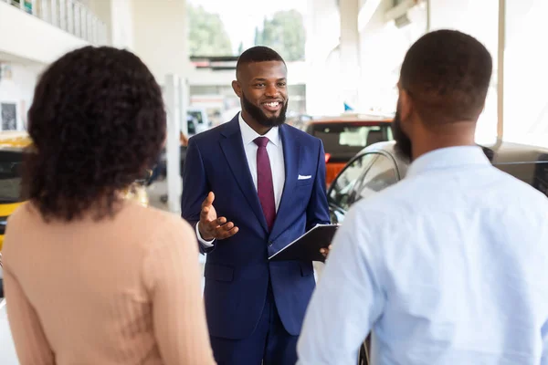 Retrato de bonito vendedor preto clientes de consultoria no moderno carro Dealership Center — Fotografia de Stock