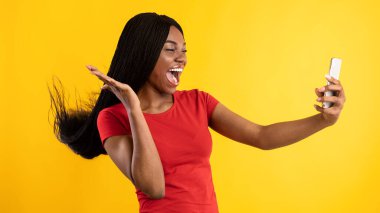 Akıllı Telefon kullanan neşeli Afrikalı Kadın Sarı Arkaplanda Selfie Yapıyor
