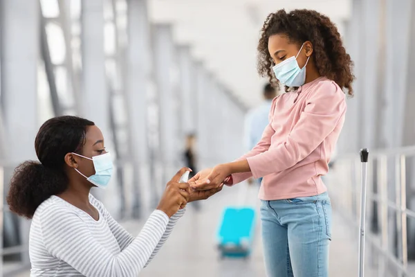 Negro familia viajando, señora usando desinfectante en niñas manos —  Fotos de Stock