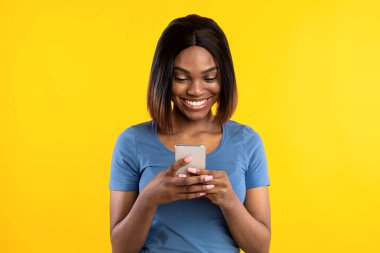 Sarı Stüdyo Arkaplanı Üzerinde Cep Telefonu Mesajı Kullanan Afrikalı Amerikalı Kadın