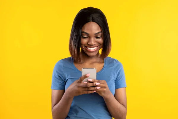 Afrikai amerikai hölgy mobiltelefon SMS-ezés sárga stúdió háttér — Stock Fotó