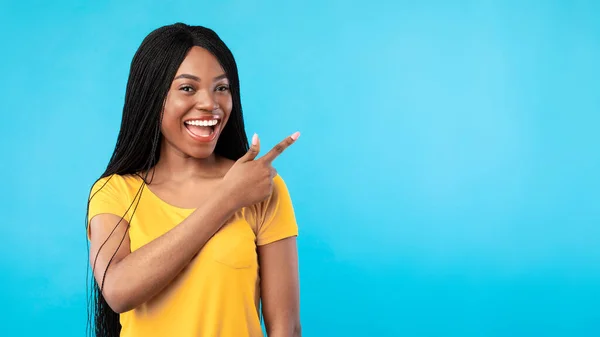 Czarna kobieta wskazujące palec poza Wyświetlanie Copyspace, Niebieskie tło — Zdjęcie stockowe