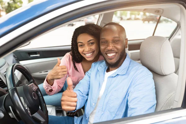 Feliz negro pareja sentado en coche gesto pulgares arriba —  Fotos de Stock