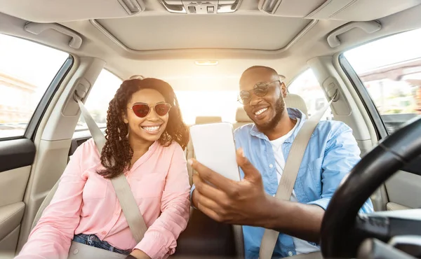 Glücklicher schwarzer Mann und Frau, die Auto fahren und Smartphone benutzen — Stockfoto