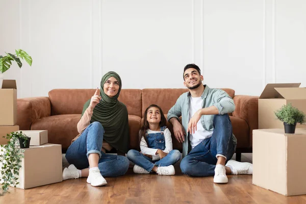 Счастливая мусульманская семья делает ремонт в новой квартире, указывая вверх — стоковое фото