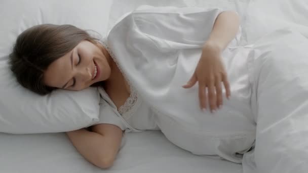 Belle femme enceinte allongée au lit et touchant tendrement son ventre — Video