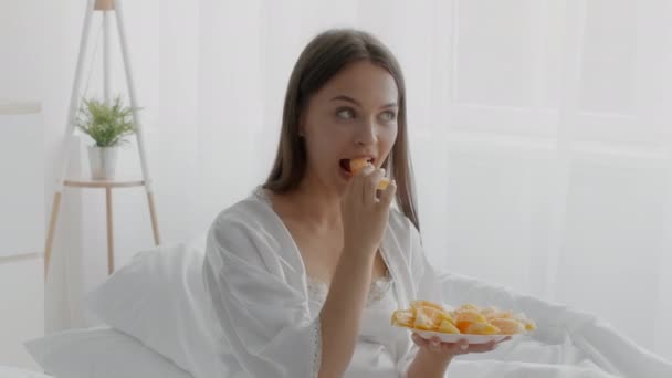妊娠栄養。幸せな若い妊娠中の女性が自宅で新鮮なオレンジフルーツを食べる — ストック動画