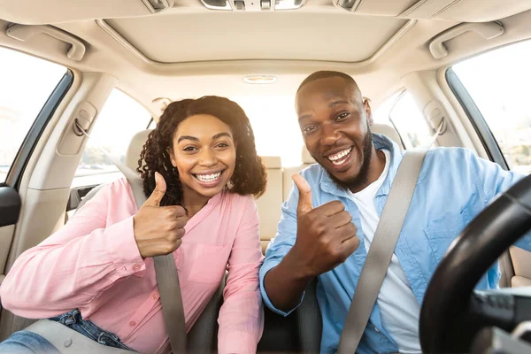 Feliz negro pareja sentado en coche gesto pulgares arriba —  Fotos de Stock