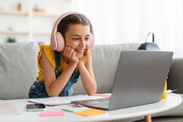 Girl sitting at desk, using laptop, wearing headset — Stock Photo, Image