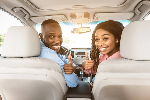 Feliz negro pareja sentado en auto gesto pulgares arriba —  Fotos de Stock