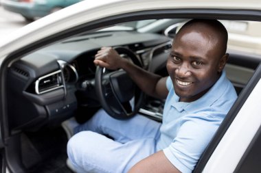 Kendinden geçmiş siyah adam yepyeni bir arabaya biniyor.