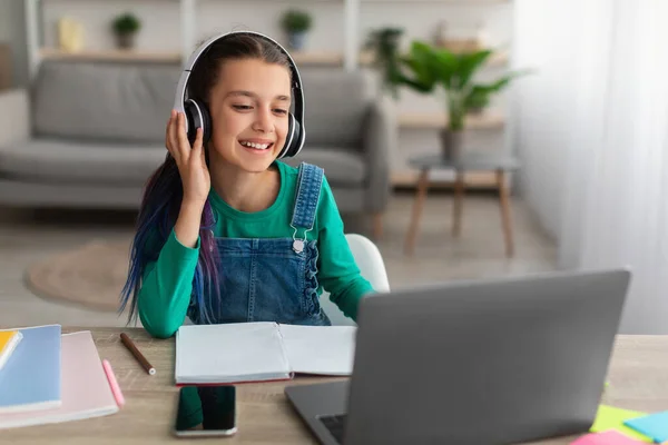 Chica sentada en la mesa, usando portátil, con auriculares — Foto de Stock