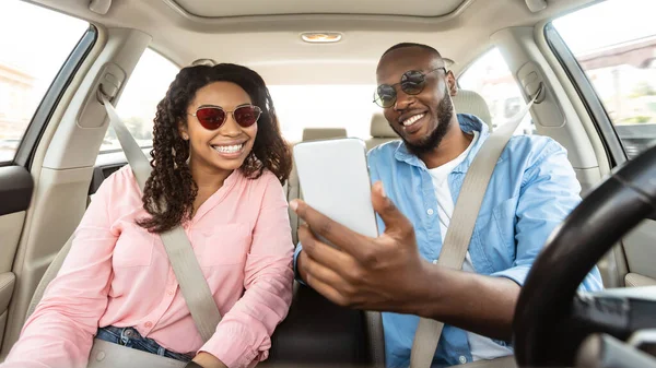 Feliz pareja negra conduciendo coche y usando el teléfono inteligente —  Fotos de Stock