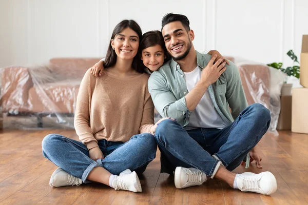 Positivo giovane famiglia guardando la fotocamera, in posa nel nuovo appartamento — Foto Stock