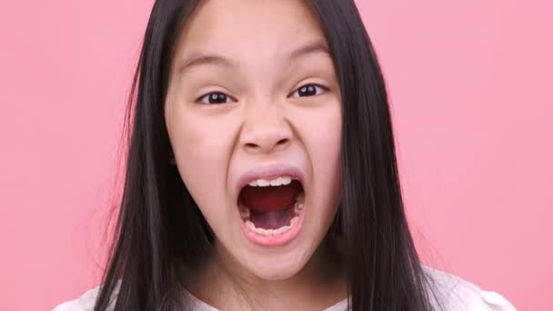 Детский гнев. Закрыть портрет разъяренной маленькой азиатской девочки, кричащей в камеру, чувствующей злость и неудовлетворенность — стоковое видео