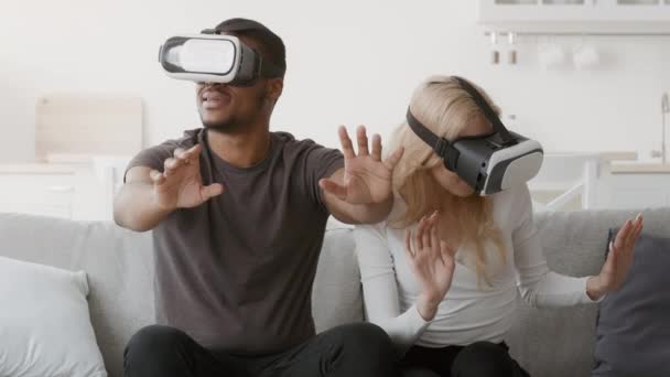 Multiethnic Couple Experiencing Virtual Reality Wearing VR Headsets At Home — Stock video