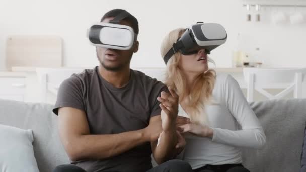 Pareja diversa asustada experimentando la realidad virtual juntos en casa — Vídeo de stock