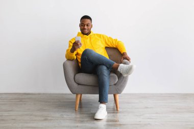 Kol Sandalyesinde oturan, Gri Arkaplan 'da oturan Afrikalı Amerikalı Adam