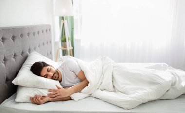 Yatma vakti. Bin yıllık Arap adam uykuda, yatak odasındaki beyaz rahat yatakta dinleniyor, boşluğu kopyalıyor.