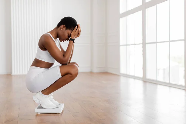 Porträt einer unglücklichen Afrikanerin, die auf Badezimmerwaagen steht — Stockfoto