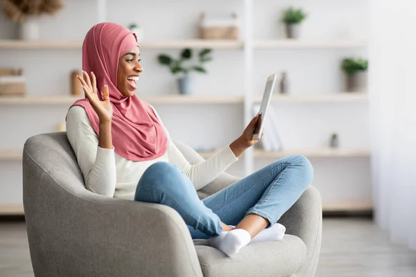 Alegre dama negra islámica haciendo videollamada con tableta digital en casa — Foto de Stock