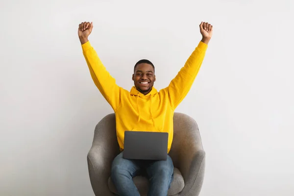 Vreugdevolle zwarte man freelancer met behulp van laptop schudden vuisten, grijze achtergrond — Stockfoto